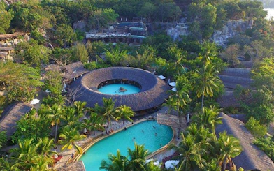 Aerial view of tropical resort with circular pool surrounded by lush greenery, Cai River, Dubai.