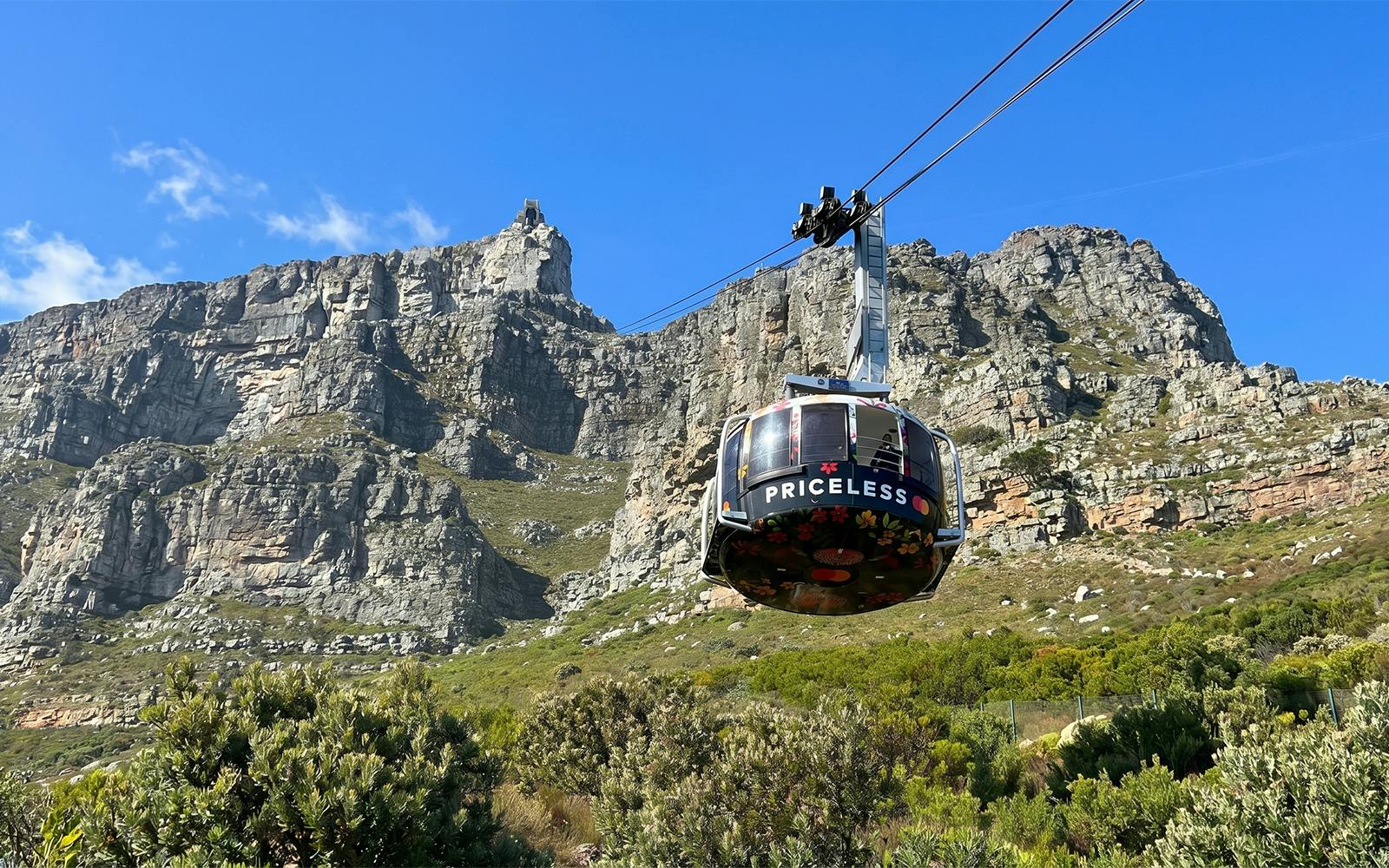 Cable car ascending Table Mountain, Cape Town, with rocky cliffs in the background.