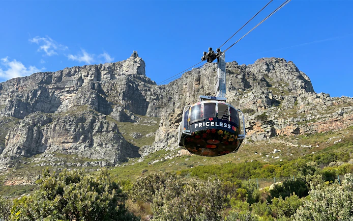 Cable car ascending Table Mountain, Cape Town, with rocky cliffs in the background.
