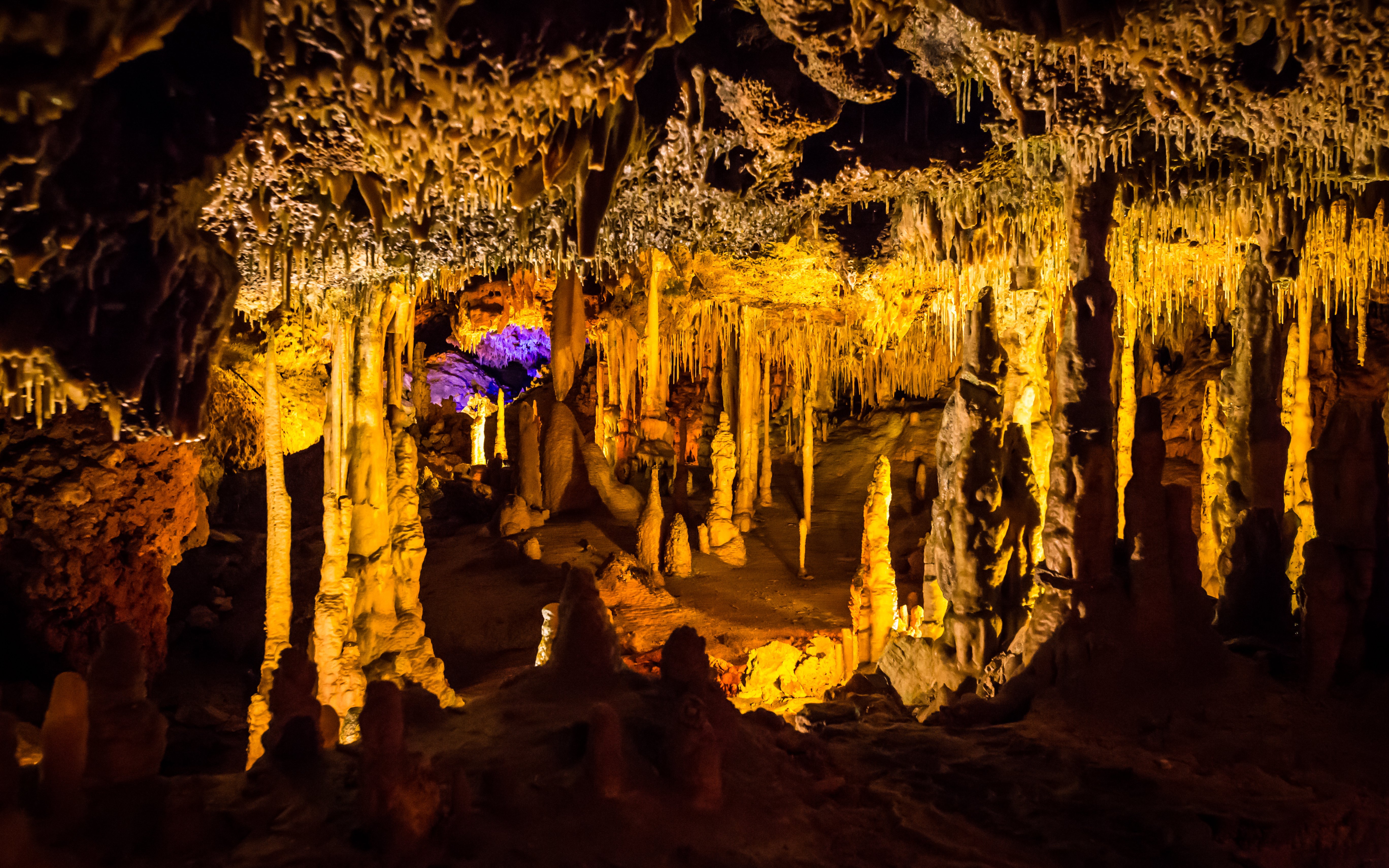 Stalactites and stalagmites in illuminated Hams Caves interior.