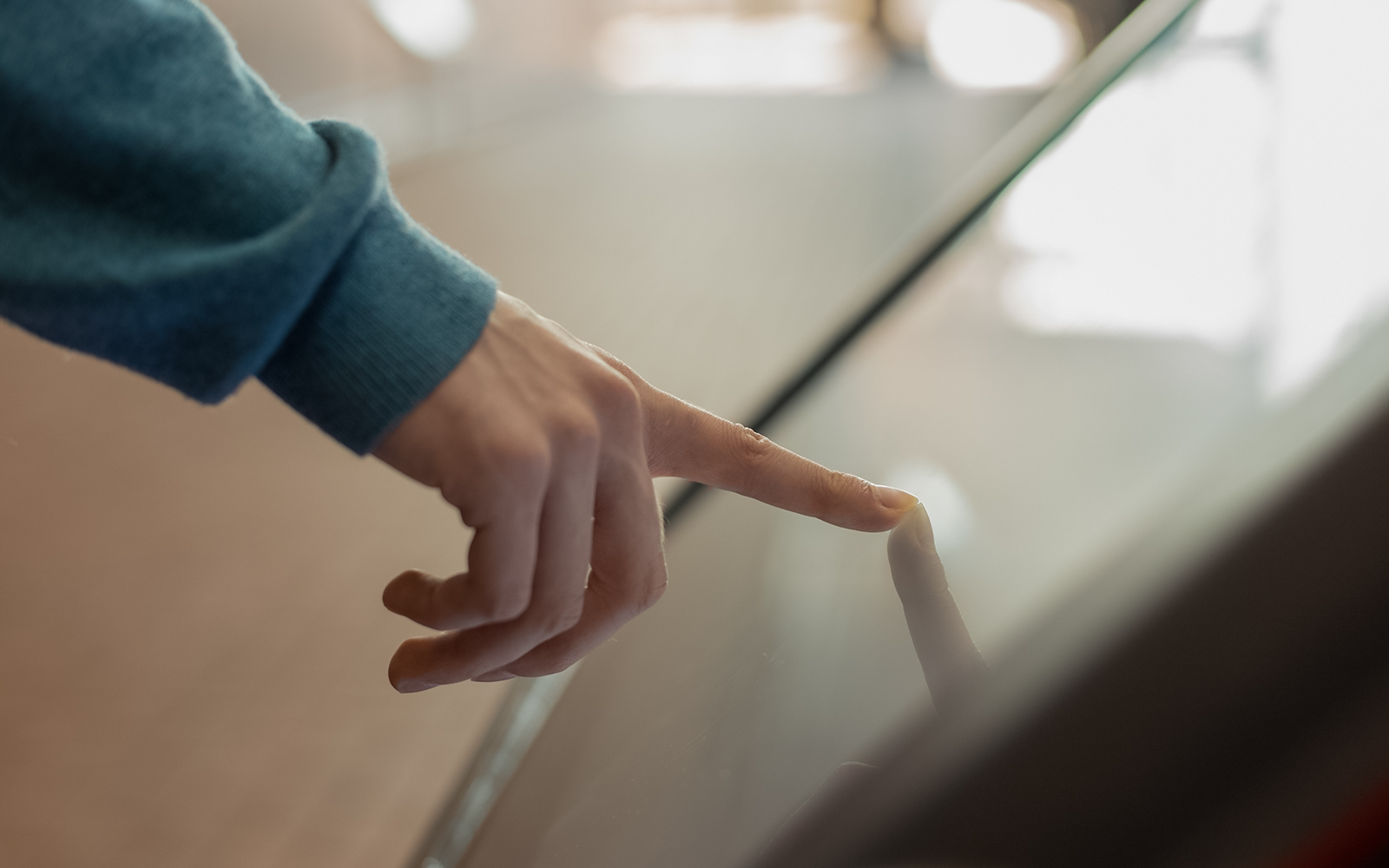 Finger interacting with a digital kiosk screen.