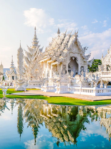 Wat Rong Khun, White Temple in Chiang Rai, Thailand, reflecting in a pond.