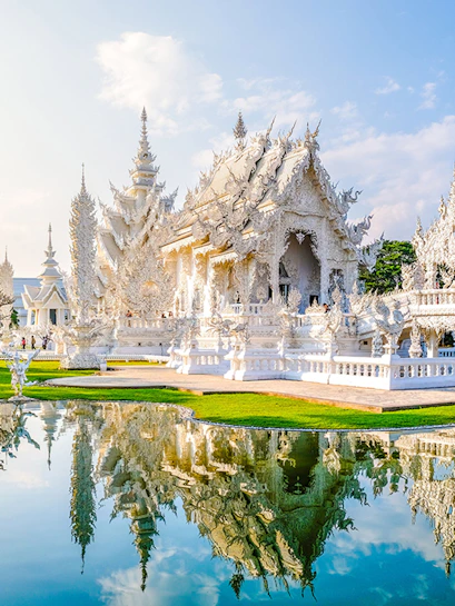 Wat Rong Khun, White Temple in Chiang Rai, Thailand, reflecting in a pond.