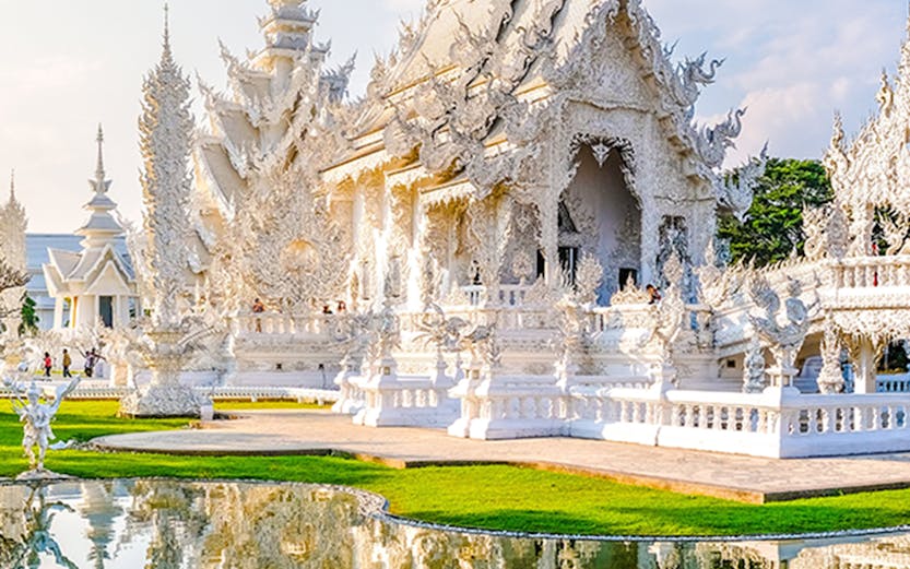 Wat Rong Khun, White Temple in Chiang Rai, Thailand, reflecting in a pond.
