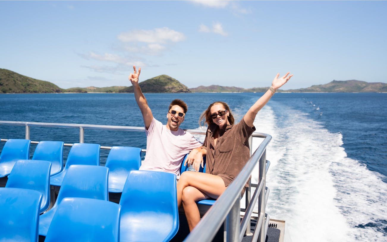 Couple enjoying cruise to Mantaray Island Resort, Fiji with ocean and islands in background.