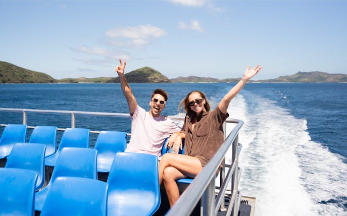 Couple enjoying cruise to Mantaray Island Resort, Fiji with ocean and islands in background.