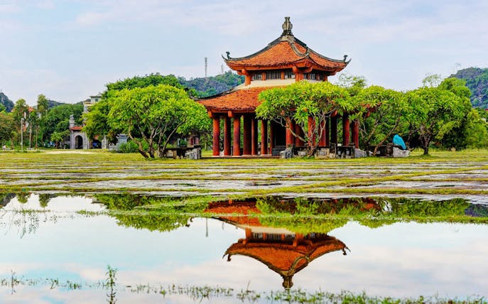 Hoa Lư Ancient Capital pavilion with red roof and columns, Ninh Bình, Vietnam.