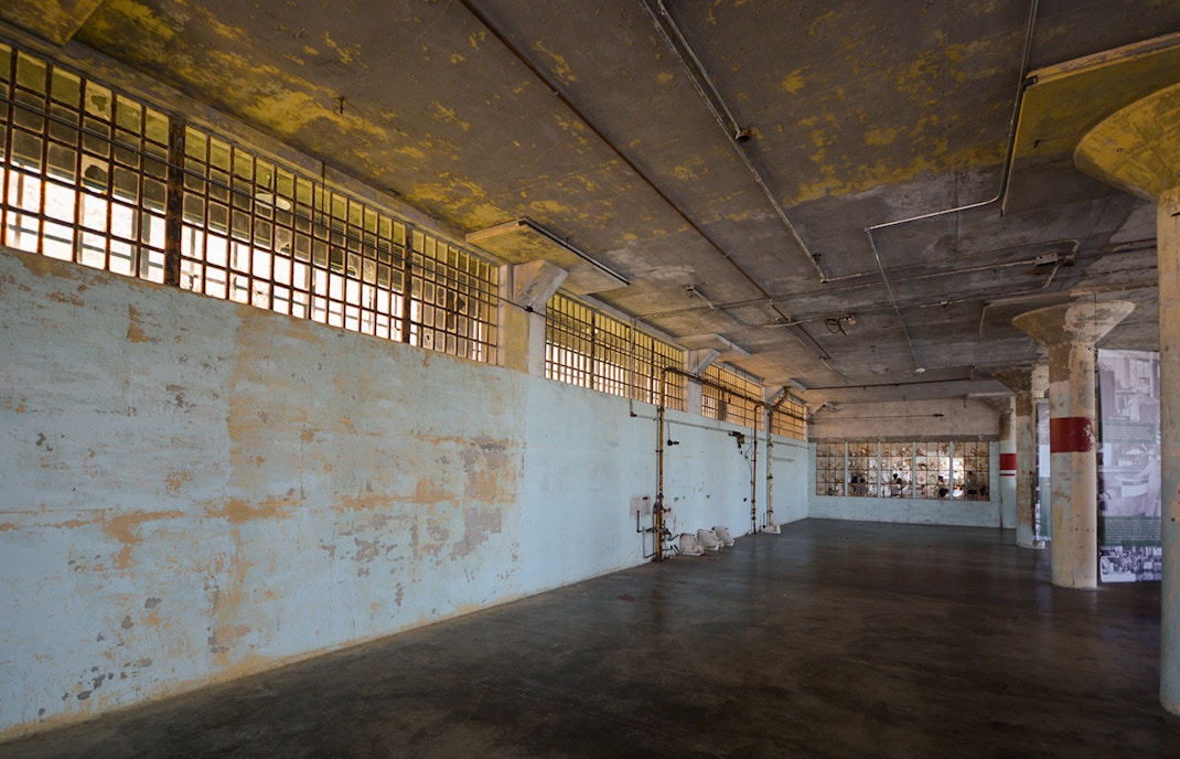 Interior of Alcatraz Island prison cell block with barred windows and peeling paint.