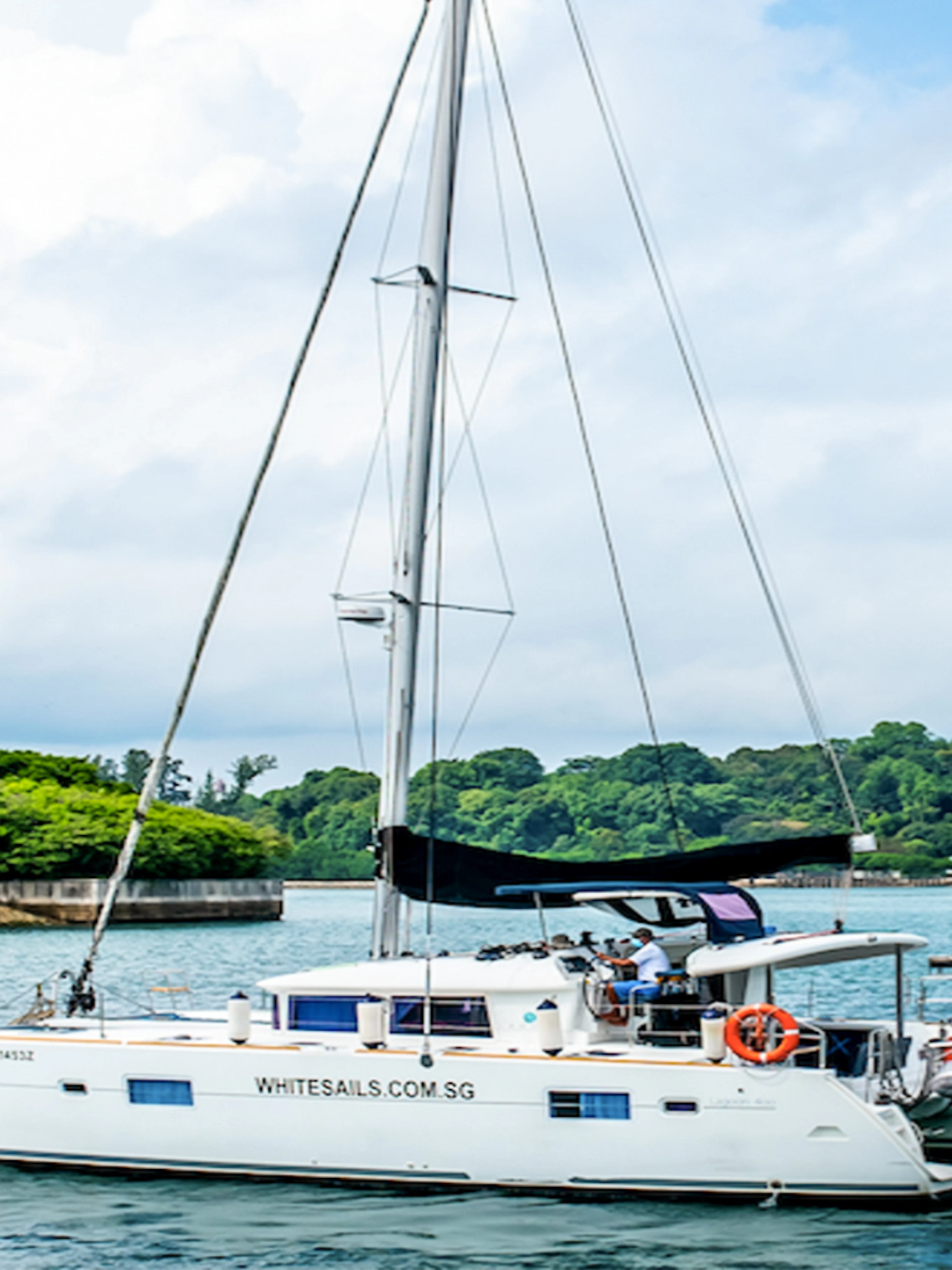 Private yacht SunRise sailing near lush green coastline.