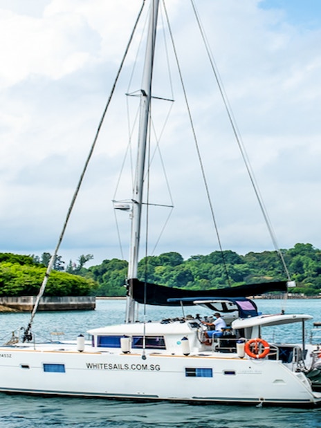 Private yacht SunRise sailing near lush green coastline.