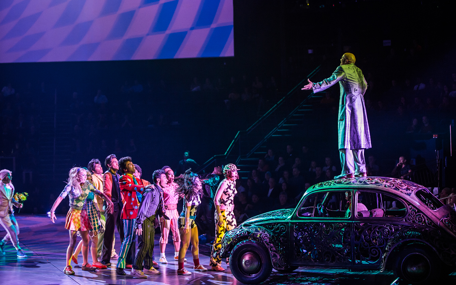 Performer on car with cast during The Beatles LOVE show.