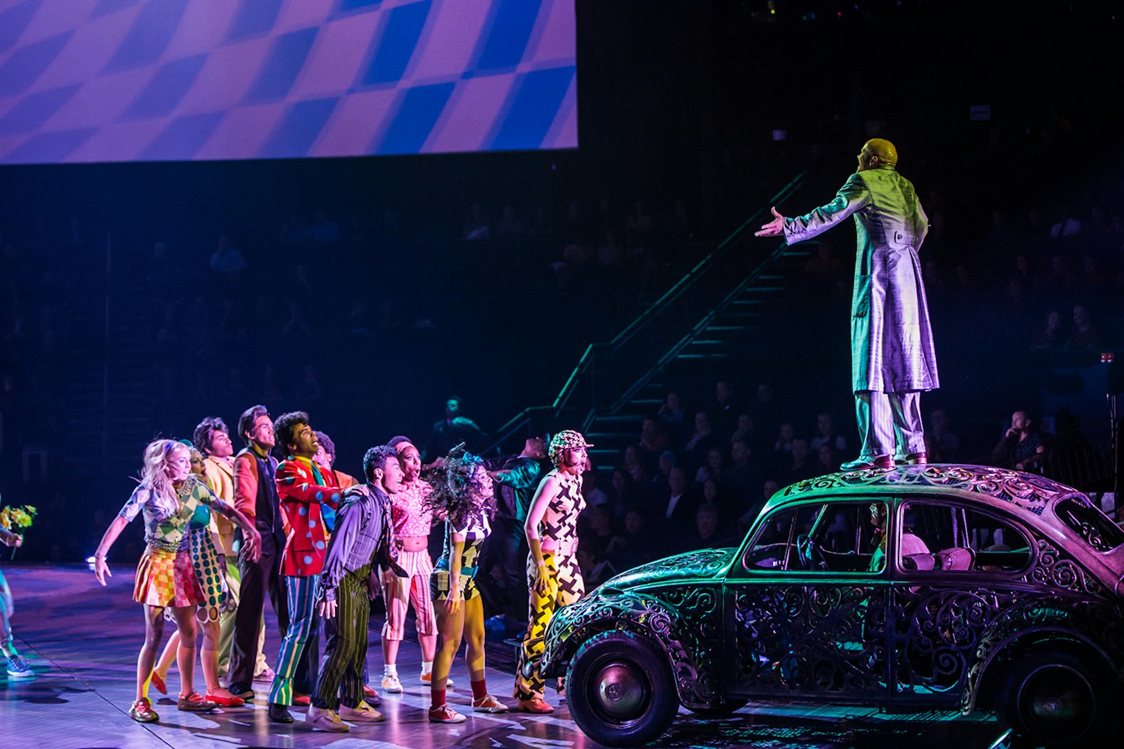 Performer on car with cast during The Beatles LOVE show.