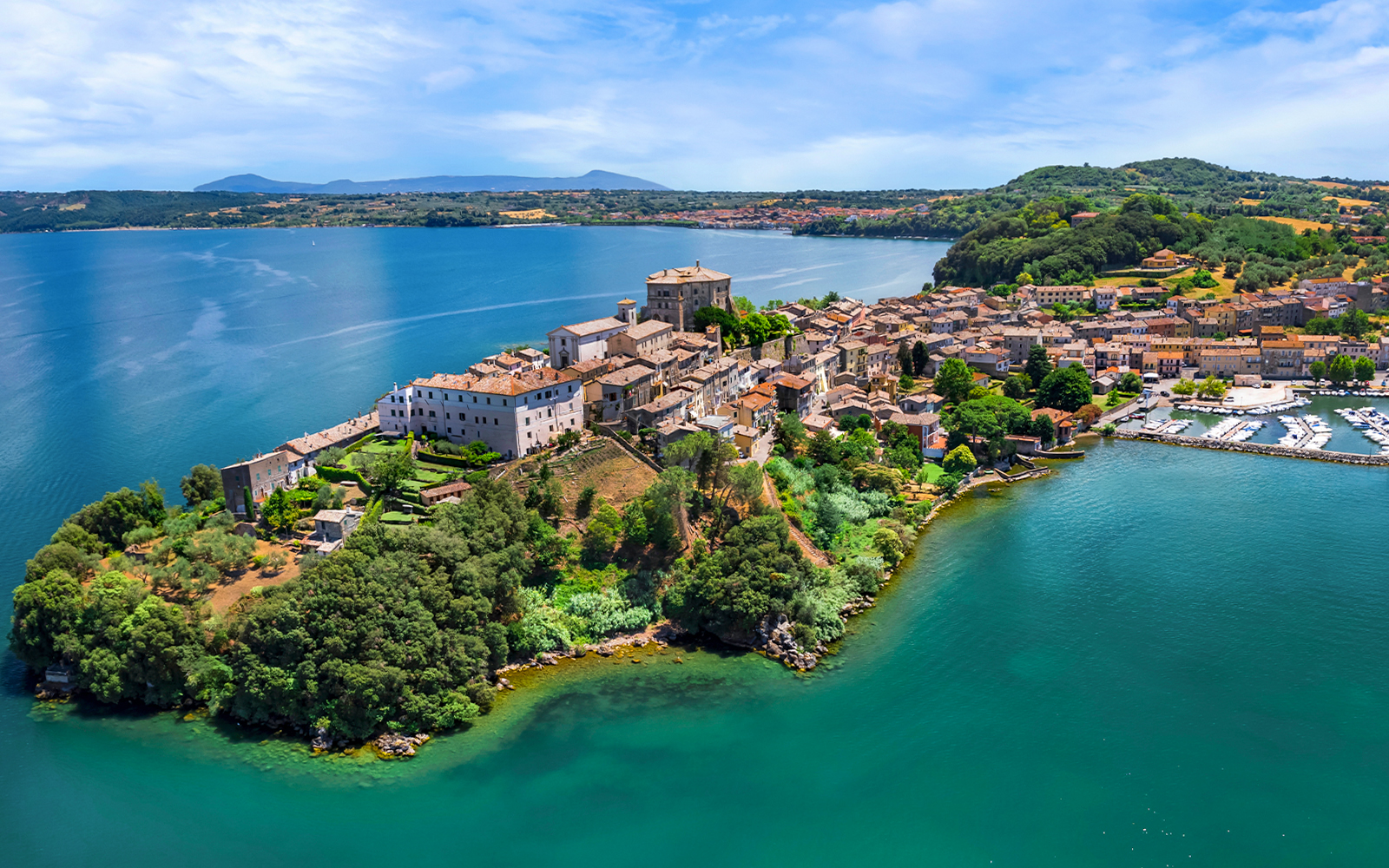Bolsena Lake view with historic buildings and lush greenery in Italy.