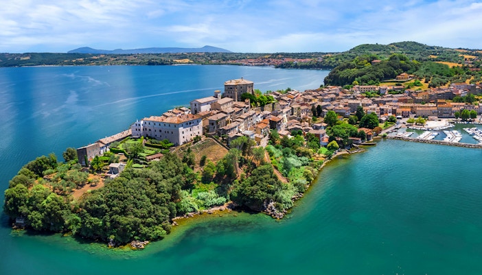 Bolsena Lake view with historic buildings and lush greenery in Italy.