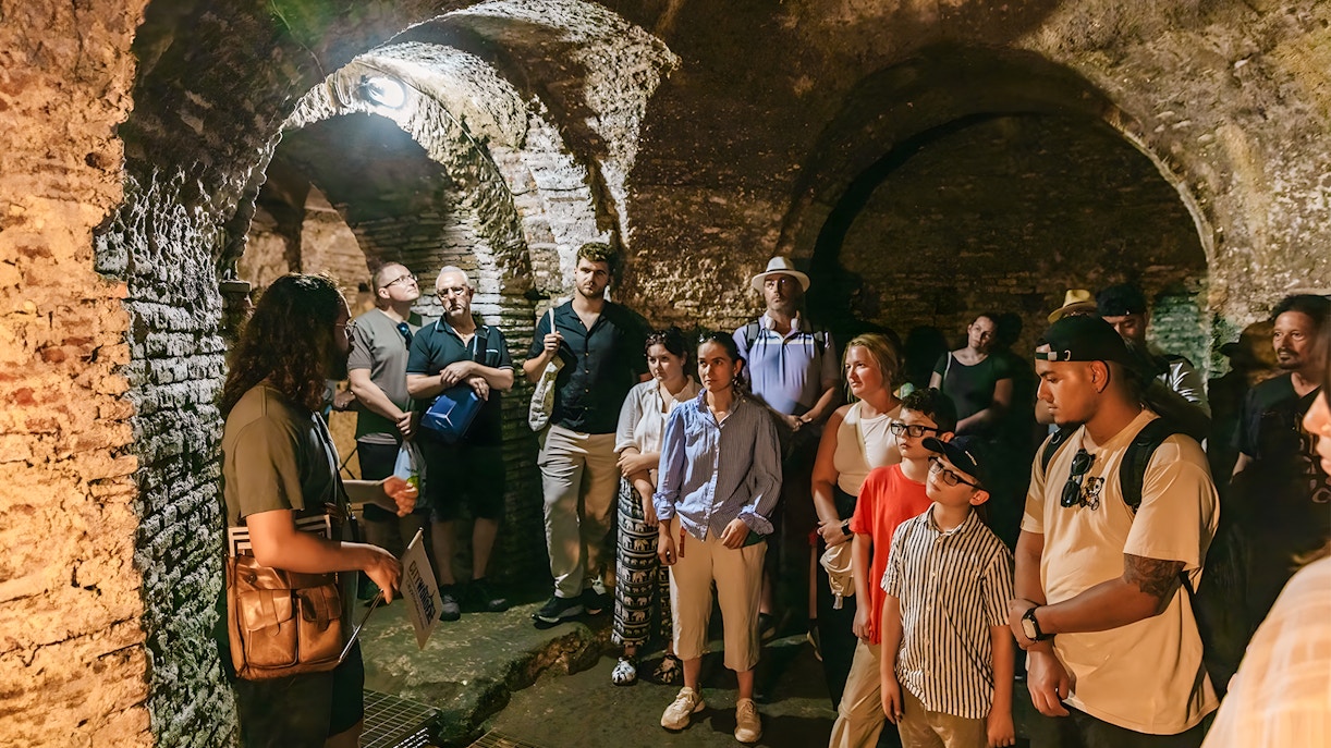 Guided tour group exploring the ancient Roman Catacombs and Basilica of San Nicola on the Appian Way in Rome, Italy