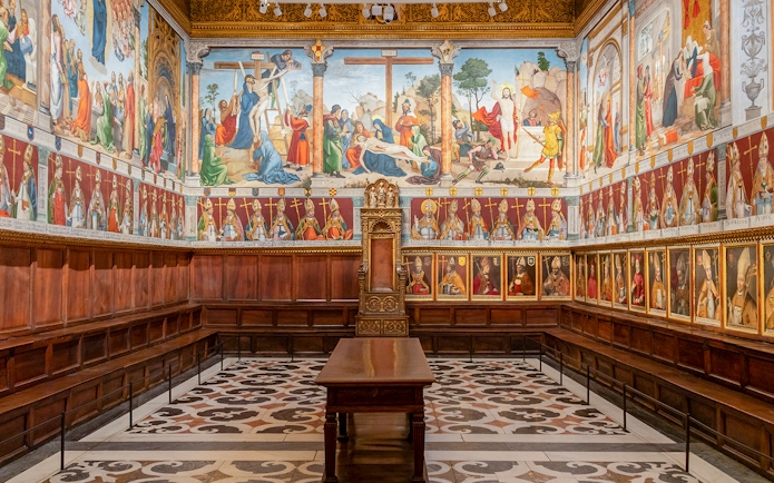 Segovia's Alcázar interior with detailed frescoes and ornate wooden seating.