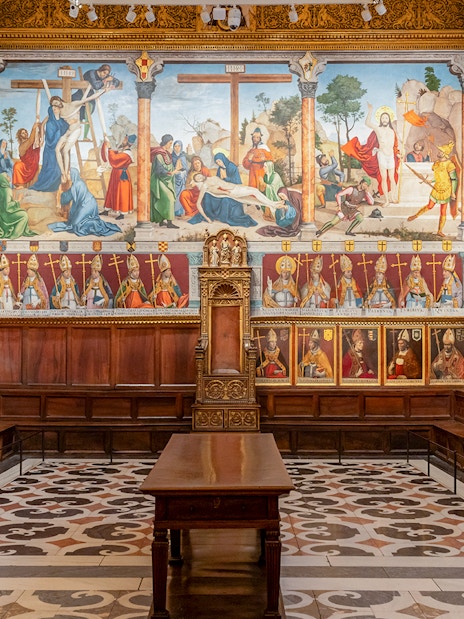 Segovia's Alcázar interior with detailed frescoes and ornate wooden seating.