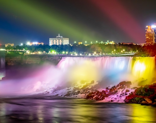 Niagara Falls illuminated in colorful lights during night show.
