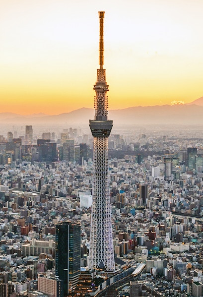 Tokyo Skytree towering over cityscape at sunset.