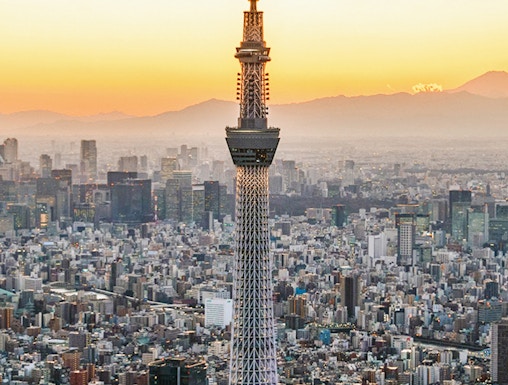 Tokyo Skytree towering over cityscape at sunset.