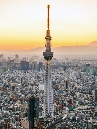 Tokyo Skytree towering over cityscape at sunset.