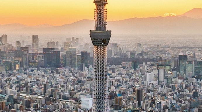 Tokyo Skytree towering over cityscape at sunset.