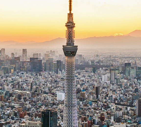 Tokyo Skytree towering over cityscape at sunset.