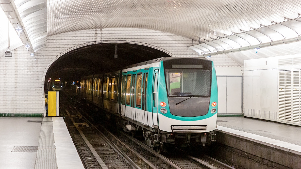 Paris Metro train arriving at a station with passengers boarding, showcasing public transport in Paris.