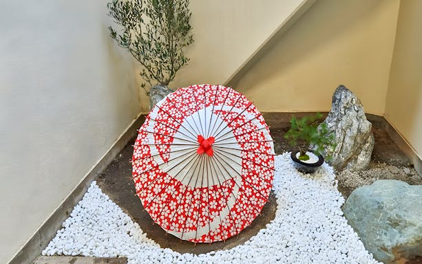 Traditional Japanese umbrella in a Tokyo garden setting with rocks and plants.