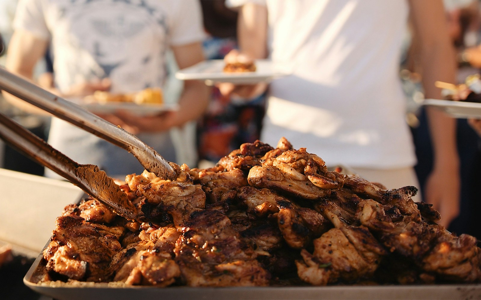 Grilled chicken being served at a sunset barbecue event.