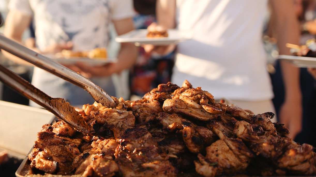 Grilled chicken being served at a sunset barbecue event.