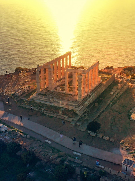 Temple of Poseidon at Cape Sounio overlooking the sea at sunset.