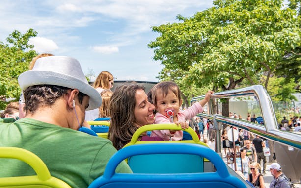 Family enjoying Paris hop-on hop-off bus tour with trees in the background.