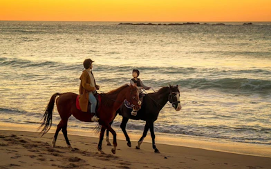 Horseback riders on a beach at sunset in Mnar, Tangier.