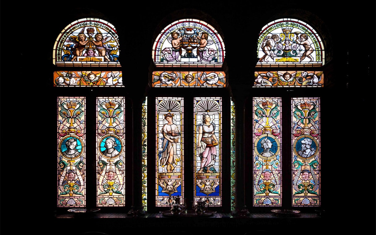 Stained glass windows depicting figures and ornate designs at Casa de Salinas.