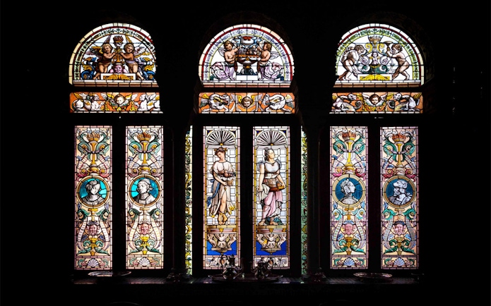 Stained glass windows depicting figures and ornate designs at Casa de Salinas.