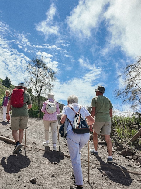 Hikers ascending Mount Vesuvius trail under a clear sky.