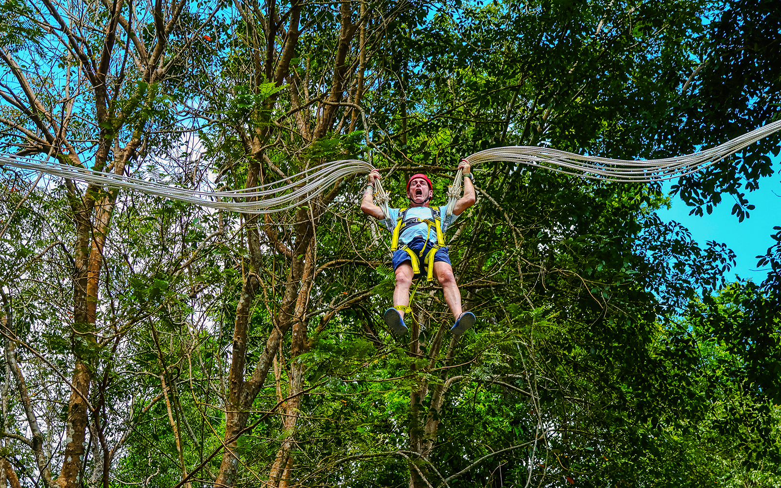 Person enjoying Slingshot Zipline at Hanuman World, surrounded by lush trees.