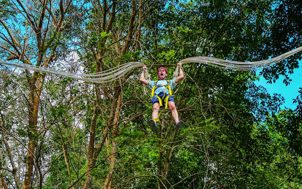 Person enjoying Slingshot Zipline at Hanuman World, surrounded by lush trees.