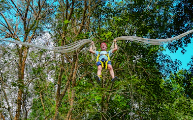 Person enjoying Slingshot Zipline at Hanuman World, surrounded by lush trees.