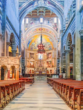 Interior of Pisa Cathedral with ornate altar and frescoed dome, part of Rome to Pisa tours.