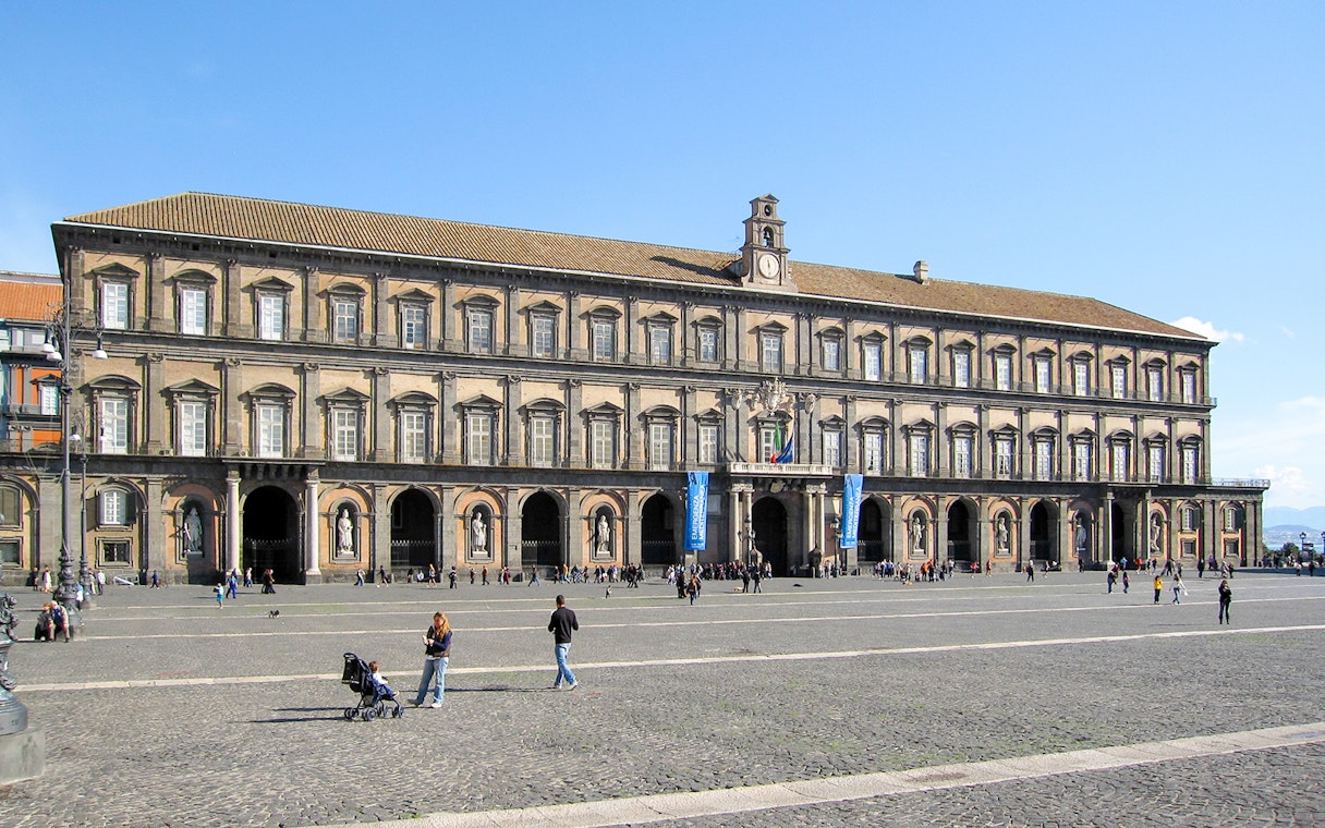 Royal Palace of Naples facade with visitors in the courtyard.
