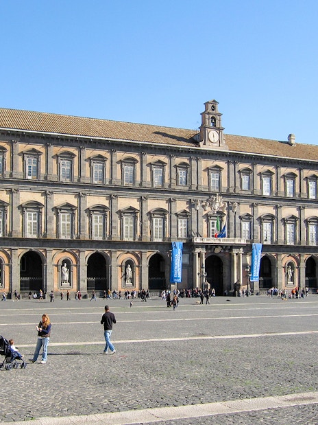 Royal Palace of Naples facade with visitors in the courtyard.