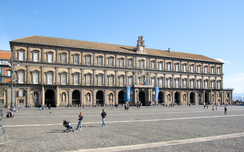 Royal Palace of Naples facade with visitors in the courtyard.