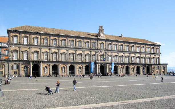 Royal Palace of Naples facade with visitors in the courtyard.