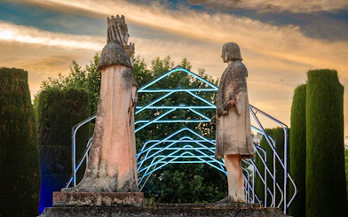 Statues in Alcazar of Cordoba garden illuminated at night.