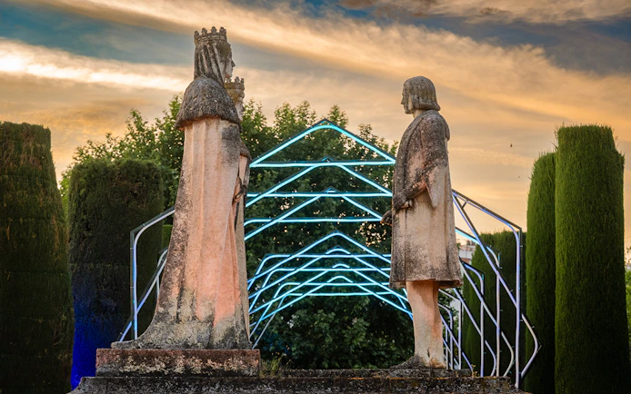 Statues in Alcazar of Cordoba garden illuminated at night.