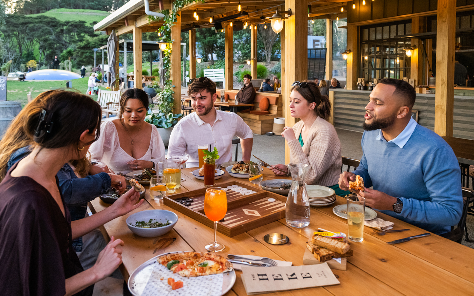 Delicacies spread out on a round table, surrounded by people gathering