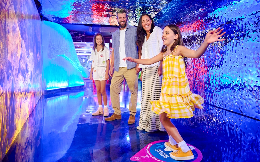 Family exploring colorful tunnel at Sea Life Melbourne.