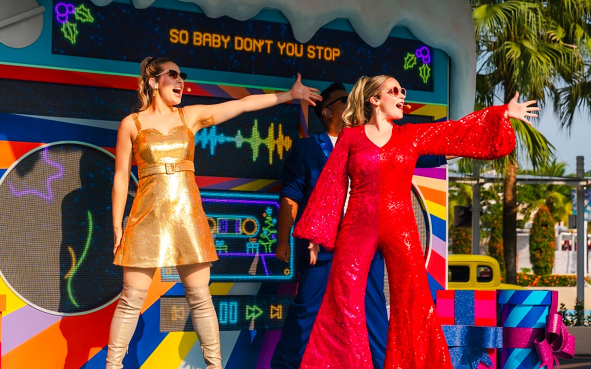 Performers in festive outfits singing at Universal Studios Singapore Christmas event.